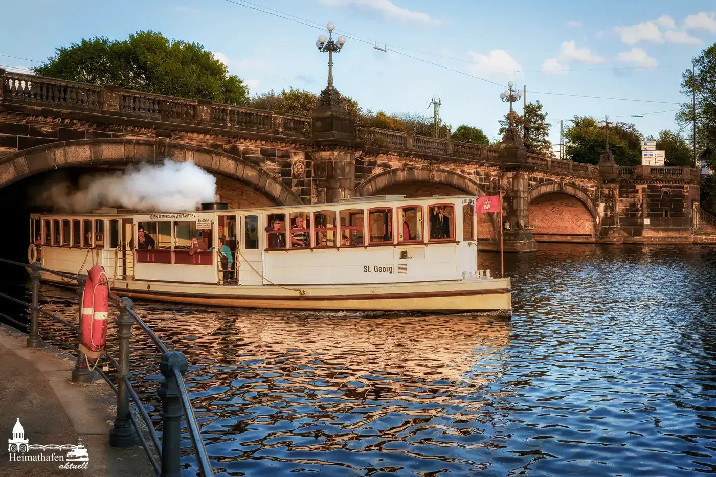 Alsterdampfer St. Georg unter der Lombardsbrücke bei Sonnenlicht auf der Außenalster.