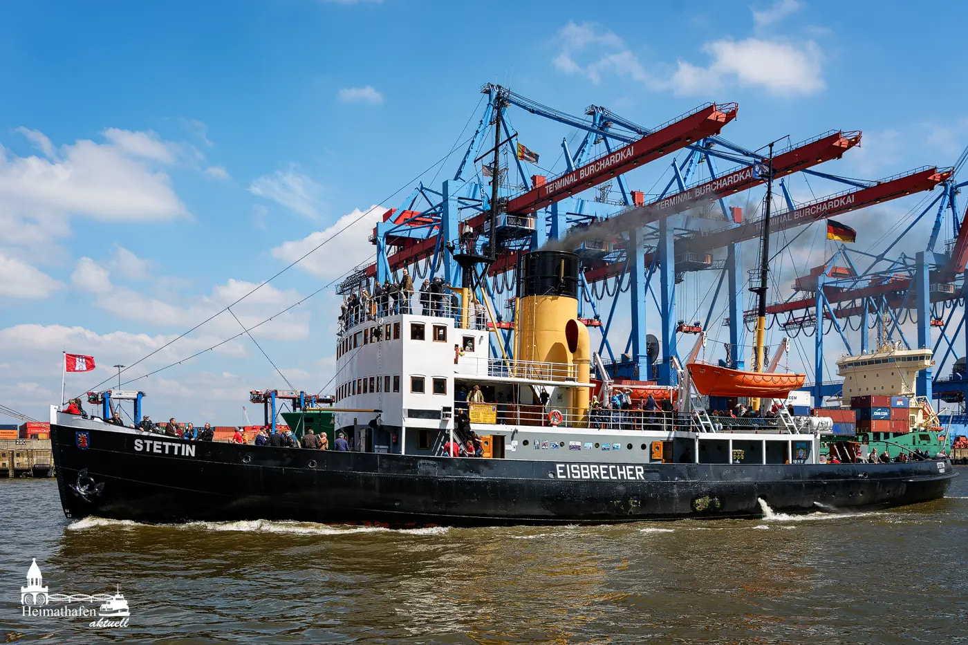 Historischer Dampf-Eisbrecher STETTIN mit gelbem Schornstein vor den Containerbrücken des Burchardkais in Hamburg.