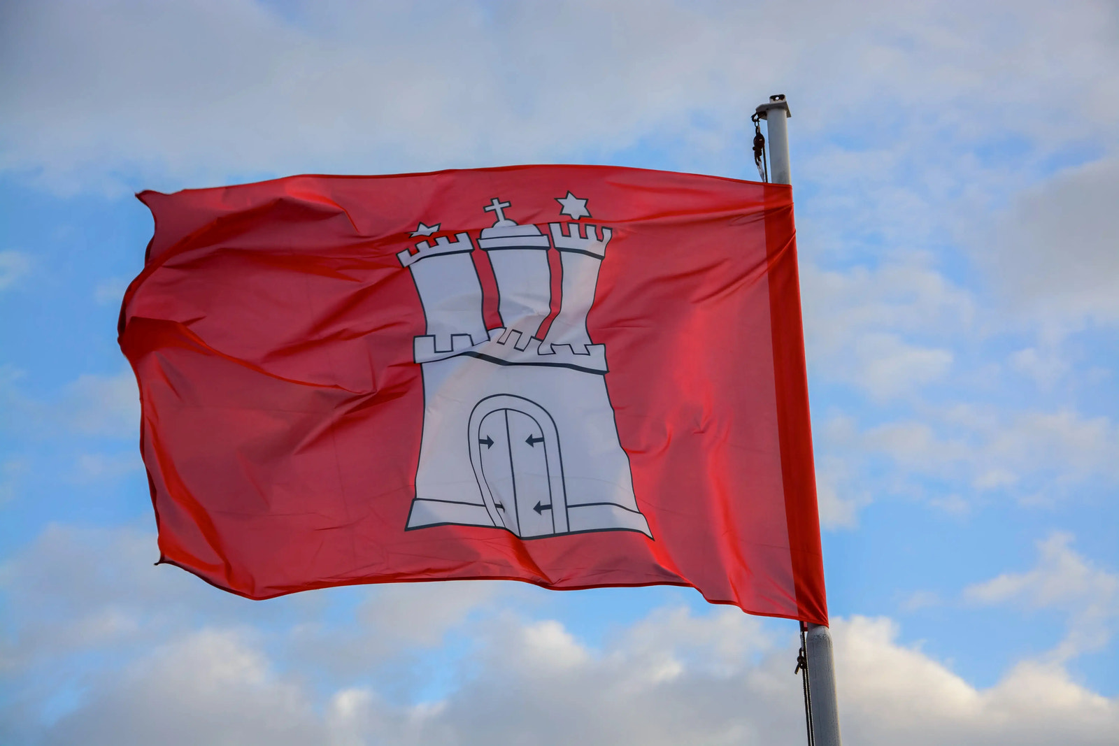 Hamburg-Flagge weht im Wind vor blauem Himmel mit Wolken
