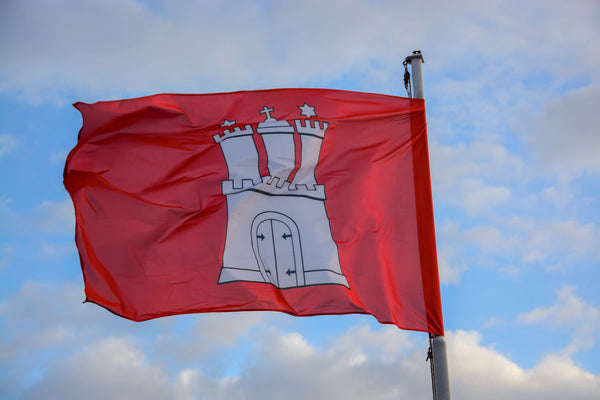 Hamburg-Flagge weht im Wind vor blauem Himmel mit Wolken