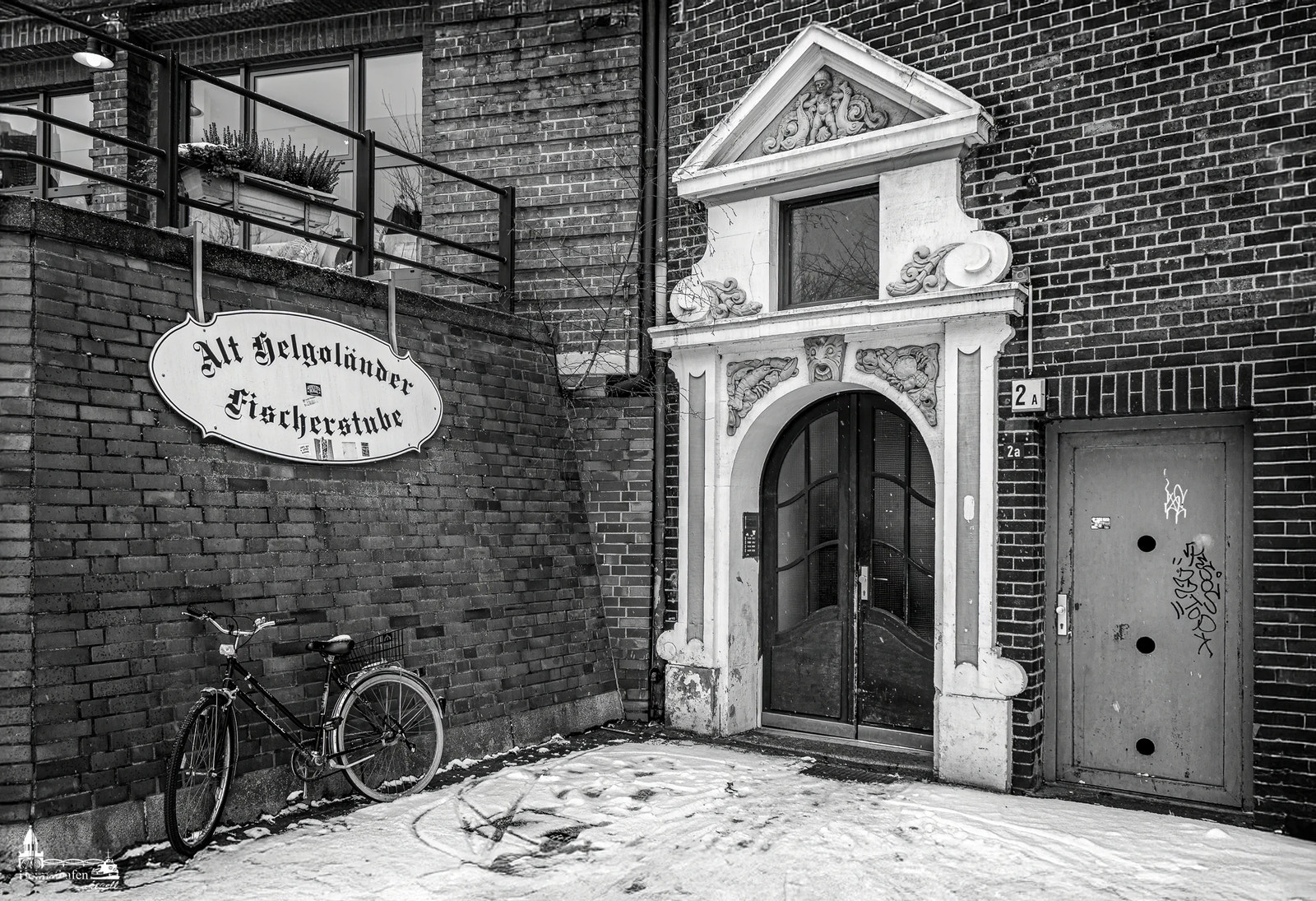 Verschneite Szene am Hamburger Fischmarkt mit der alten Helgoländer Fischerstube, verziertem Hauseingang und nostalgischem Fahrrad.