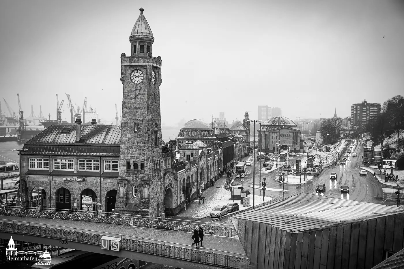 Landungsbrücken mit Pegelturm im Winter, Schneefall und nebligem Hafenhintergrund.