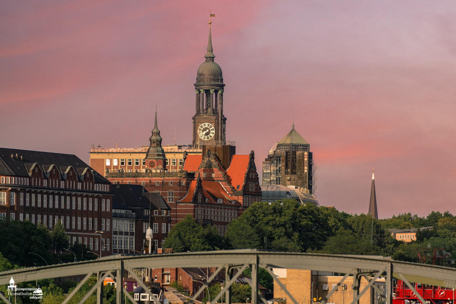 Die Abendsonne taucht Hamburgs Wahrzeichen, den Michel, in warmes Licht. Der Himmel leuchtet rosa über den historischen Fassaden und dem berühmten Uhrturm.