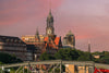 Die Abendsonne taucht Hamburgs Wahrzeichen, den Michel, in warmes Licht. Der Himmel leuchtet rosa über den historischen Fassaden und dem berühmten Uhrturm.