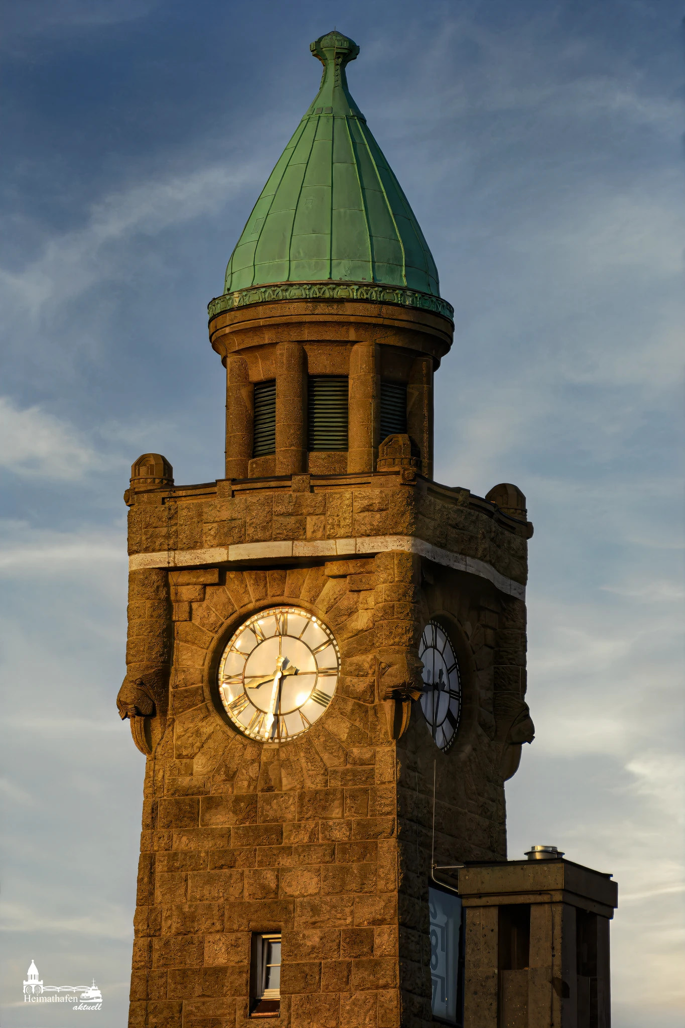 Pegelturm Hamburg Landungsbrücken im goldenen Sonnenlicht mit grünem Kupferdach und Uhrturm.