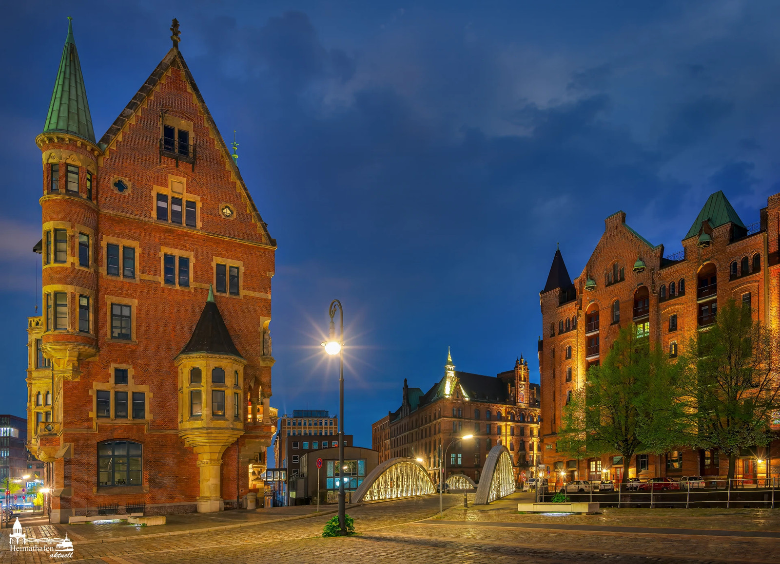 Beleuchtete Speicherstadt in der Hamburger HafenCity bei Abenddämmerung mit Brücke und historischen Gebäuden