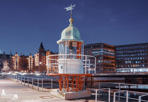 Historisches Leuchtfeuer in der Hamburger HafenCity bei Nacht, mit beleuchteter Speicherstadt im Hintergrund