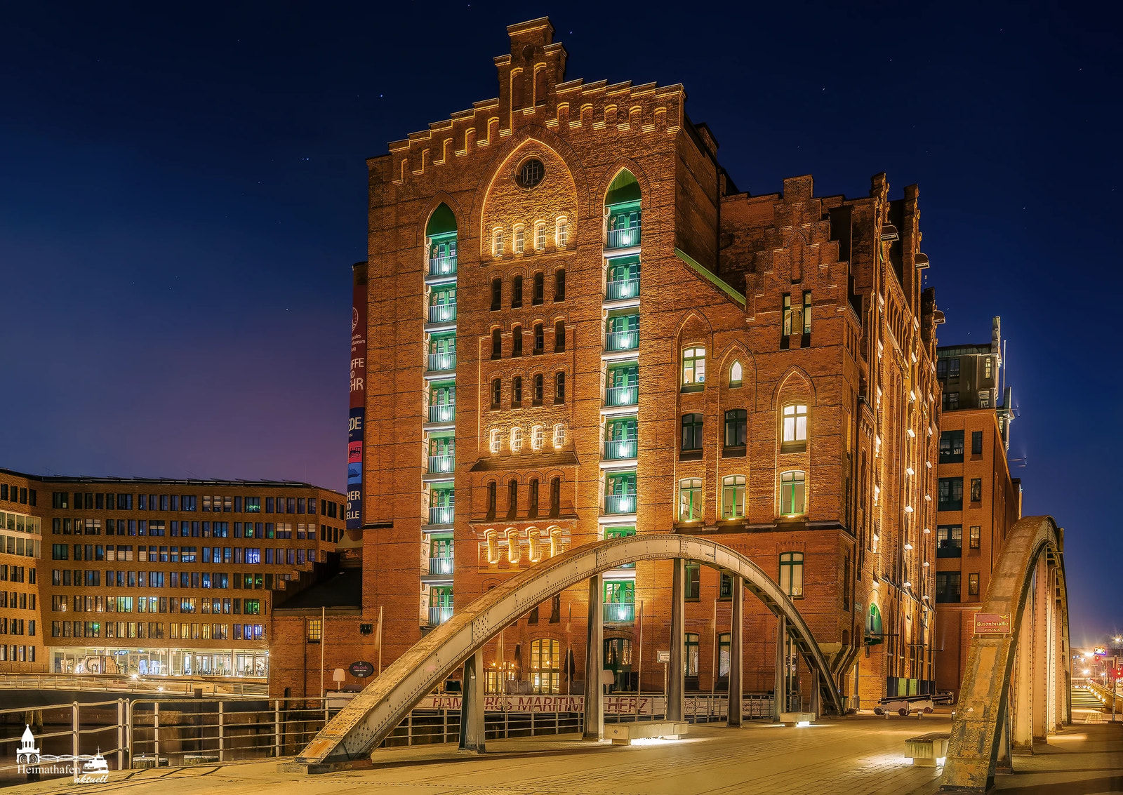 Internationales Maritimes Museum Hamburg bei Nacht mit beleuchtetem Backsteingebäude und Brücke in der HafenCity