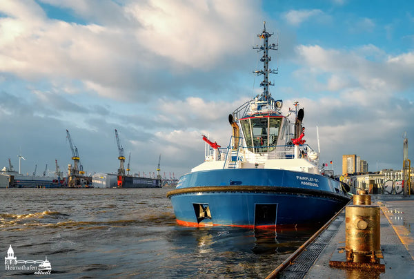 Schlepper FAIRPLAY 91 im Hamburger Hafen vor Docklandschaft und Kränen bei Sonne und Wolken