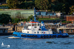 Der Schlepper FAIRPLAY VI aus Rostock fährt vor den Landungsbrücken in Hamburg entlang. Im Hintergrund sind die bekannten grünen Kupferdächer der Station zu sehen.
